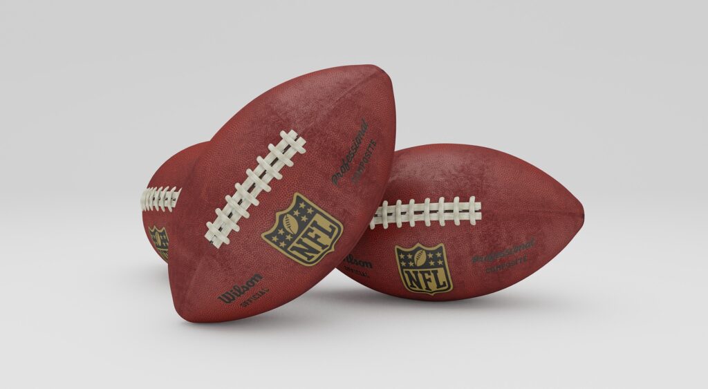 2 football balls next to each other. What does the NFL & JLO have in common?