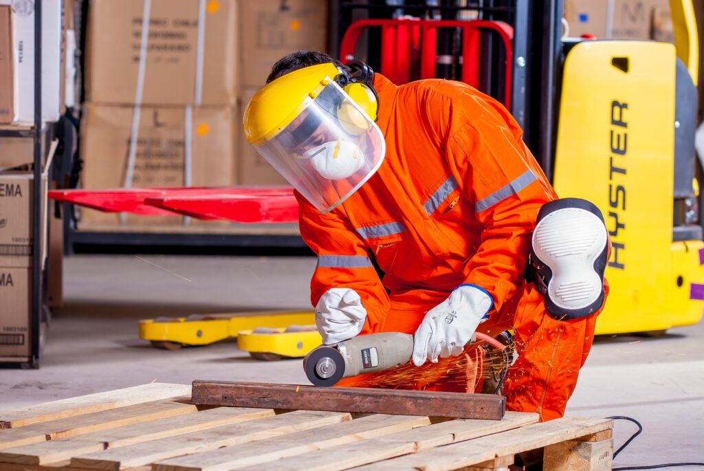 Hearing Protection At Work. Man cutting metal in protective gear on work.