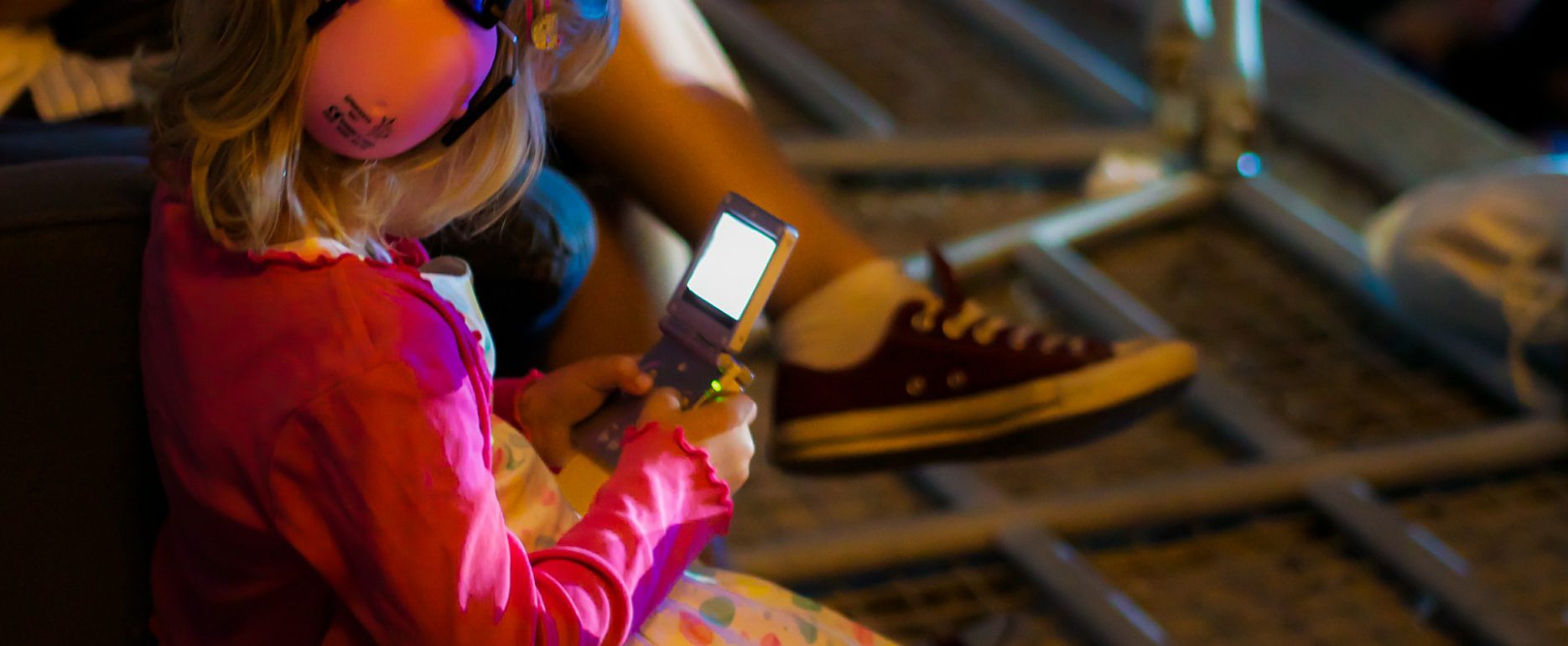 Little girl with ear muffs looking at the phone. Types of Hearing Protection