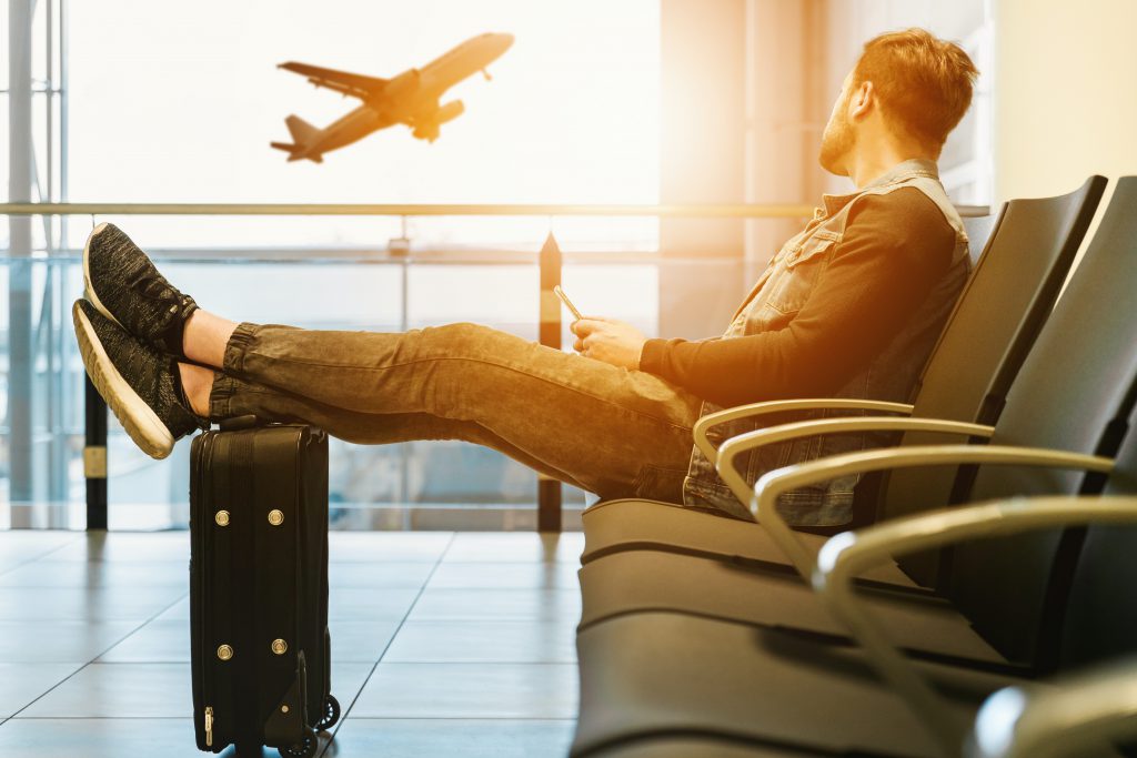 Traveling With Hearing Loss. Man looking at the plain with his feet on the luggage.