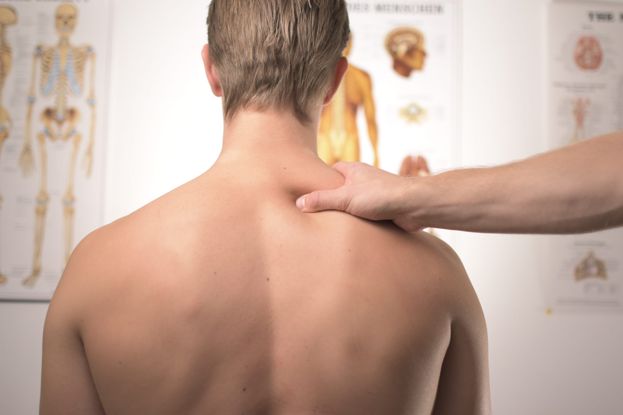 Man on medical examination with doctor checking his back