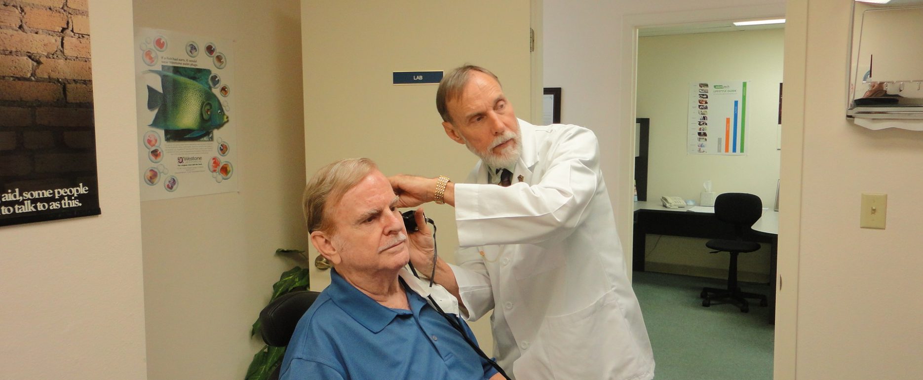 What to expect at the audiologist? Man going throug a hearing check with doctor examining him