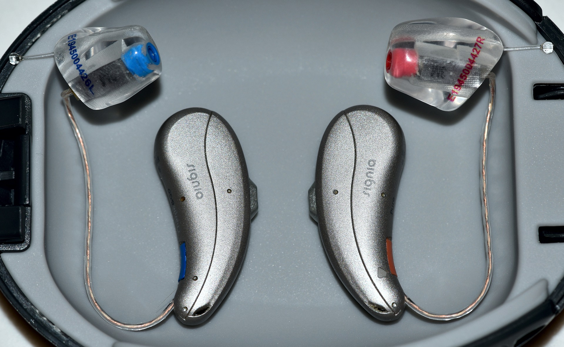 Hearing aid devices on the gray background. which brand of hearing aid is the best?
