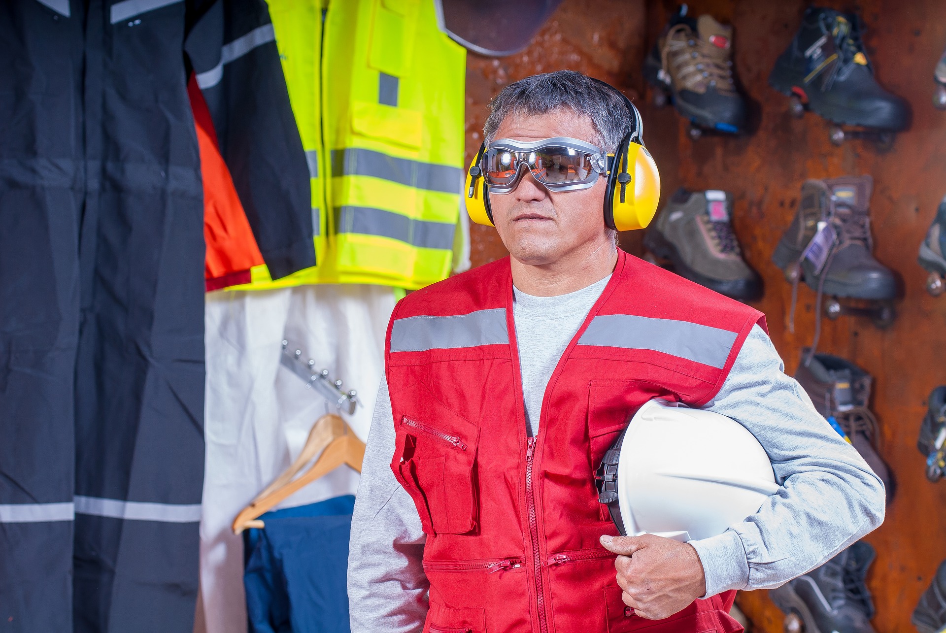 Industrial Deafness. Worker with helm under arm, googles, and hearing protection looking straight