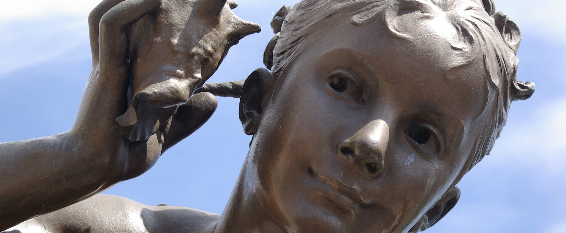 Statue with boy holding a shell near his ear and hearing it