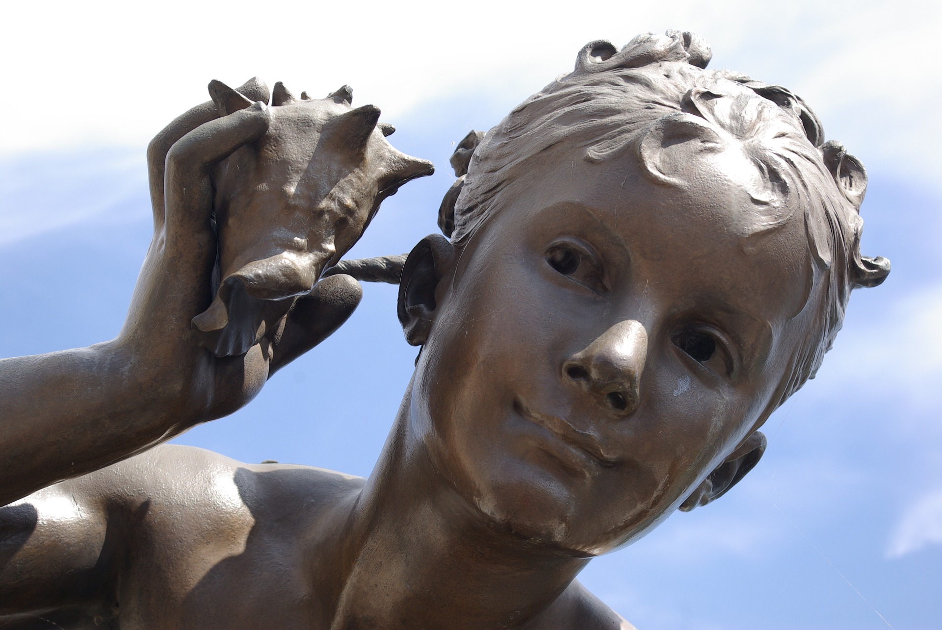 Statue with boy holding a shell near his ear and hearing it