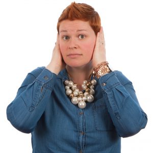 Woman holding both her hands on her ears and watching at the camera. Degree of hearing loss