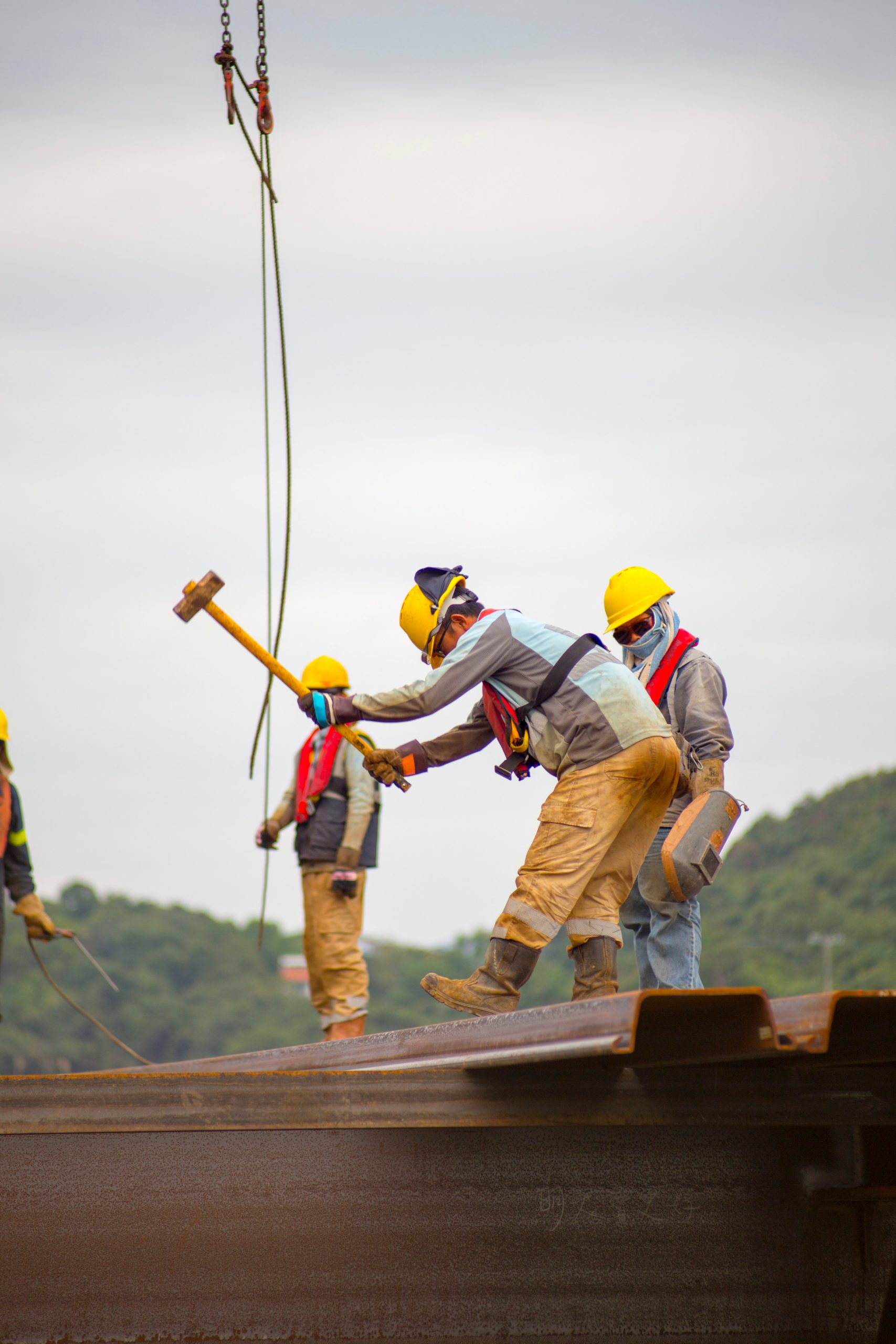 3 man working on the construction site, hammering parts of the metal.