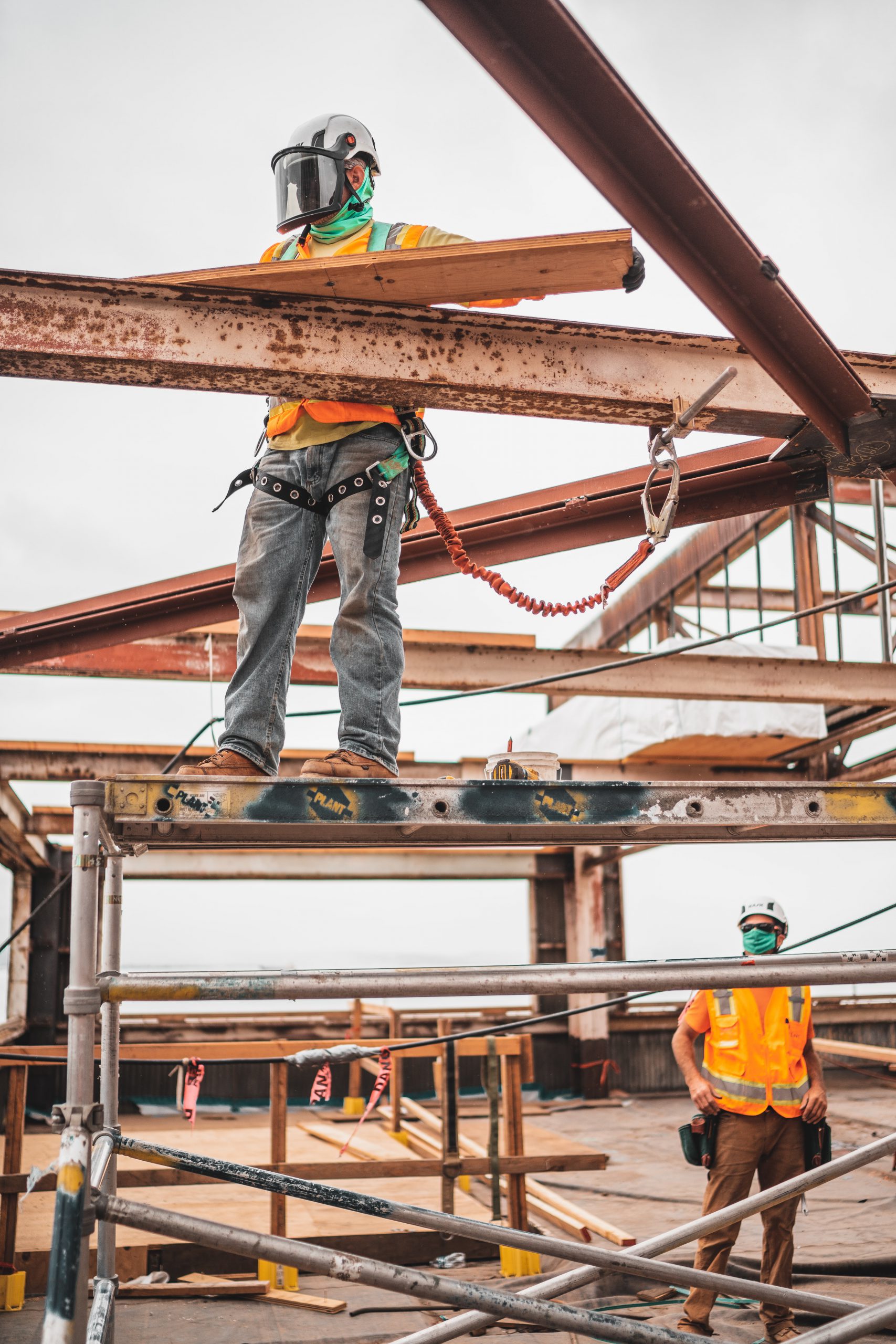 Symptoms of Industrial Deafness.Man standing on the metal construction and working while the other worker looks at him