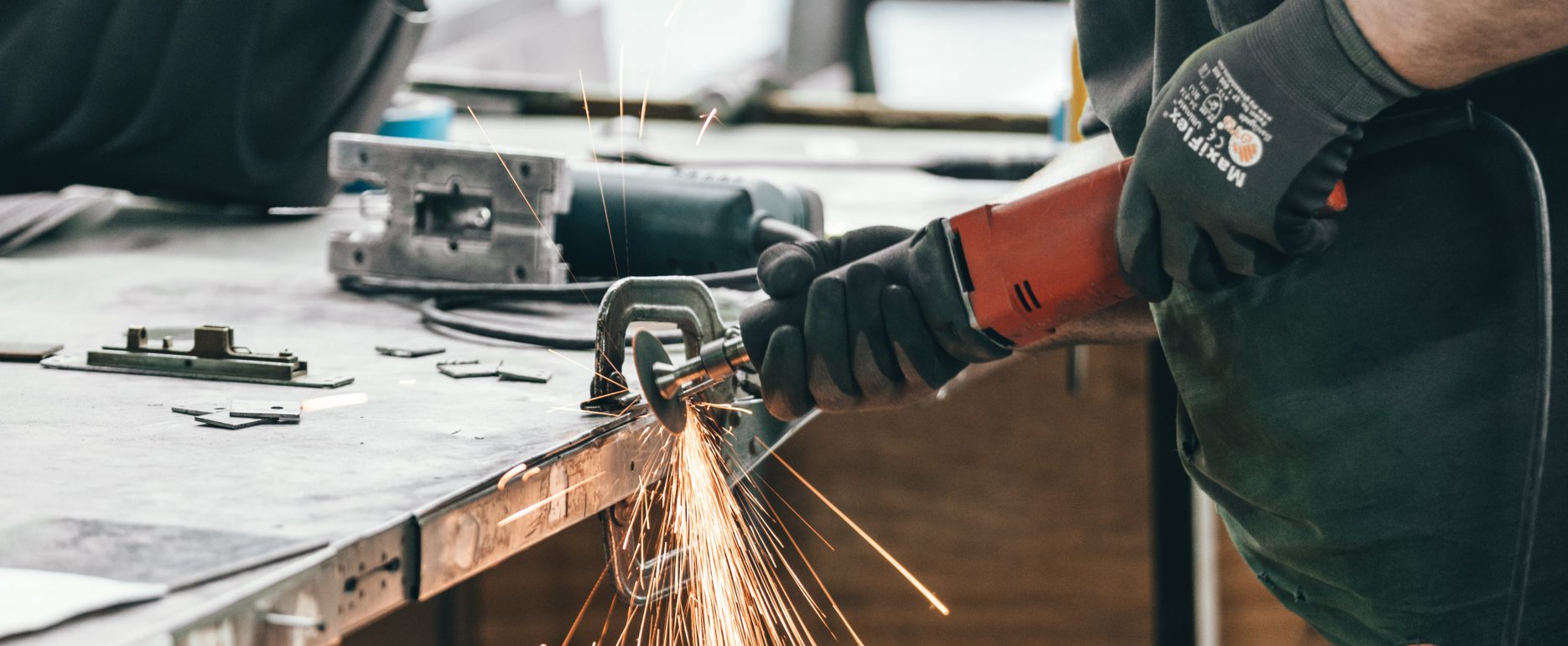 Worker with a mask grinding a metal part.