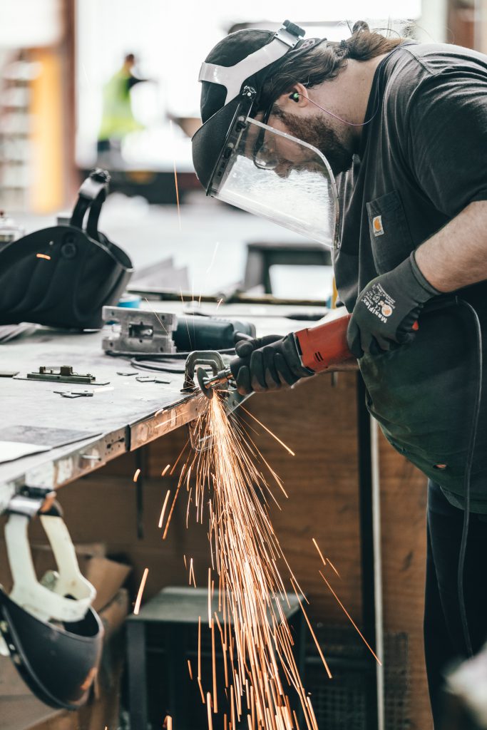 Worker with a mask grinding a metal part.