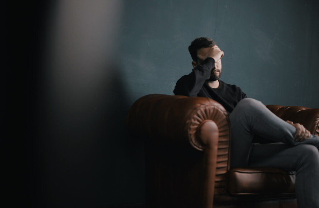 Stressed man sitting on the leather couch. Can Stress Cause Tinnitus?